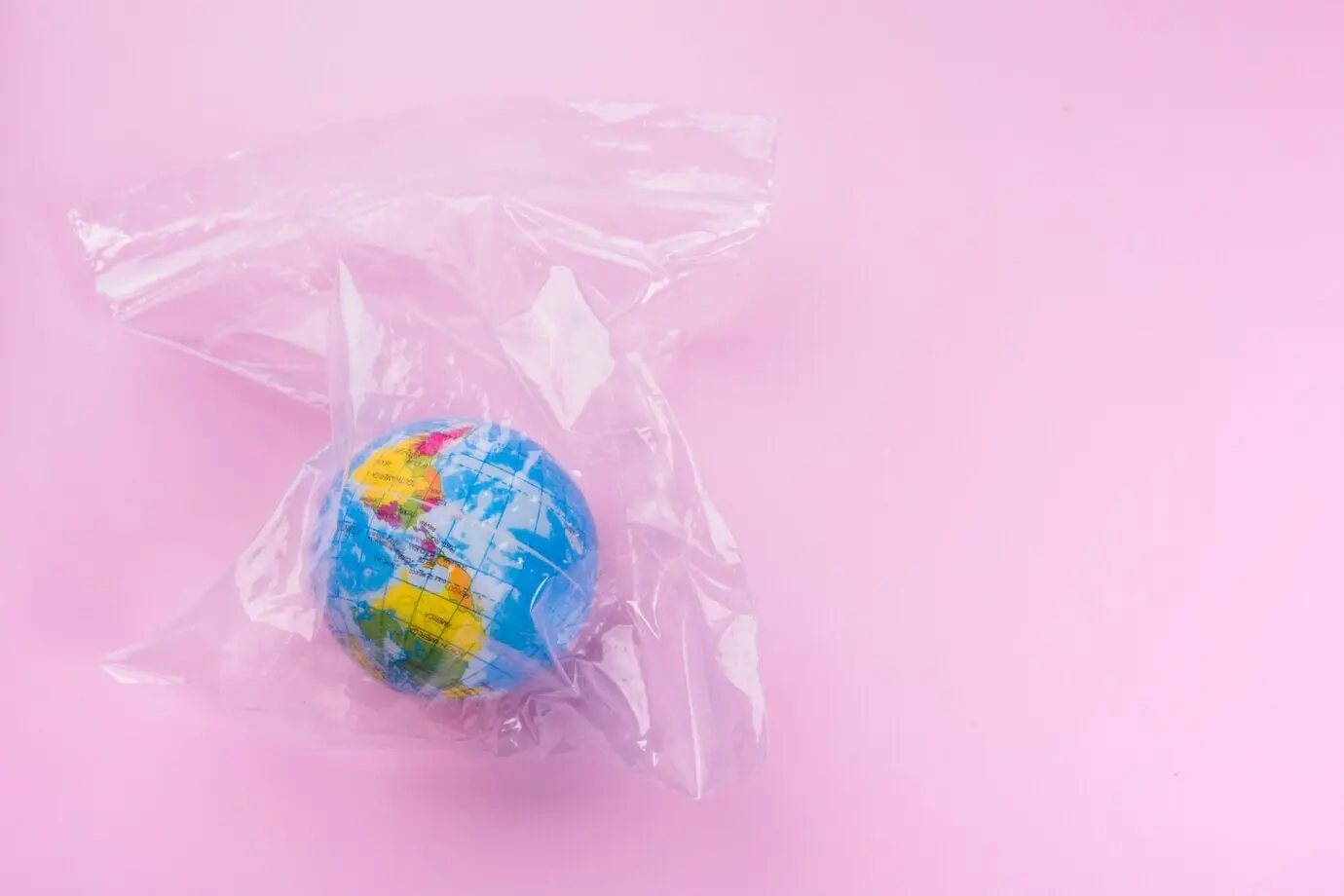 Глобус в полиэтиленовом пакете на розовом фоне